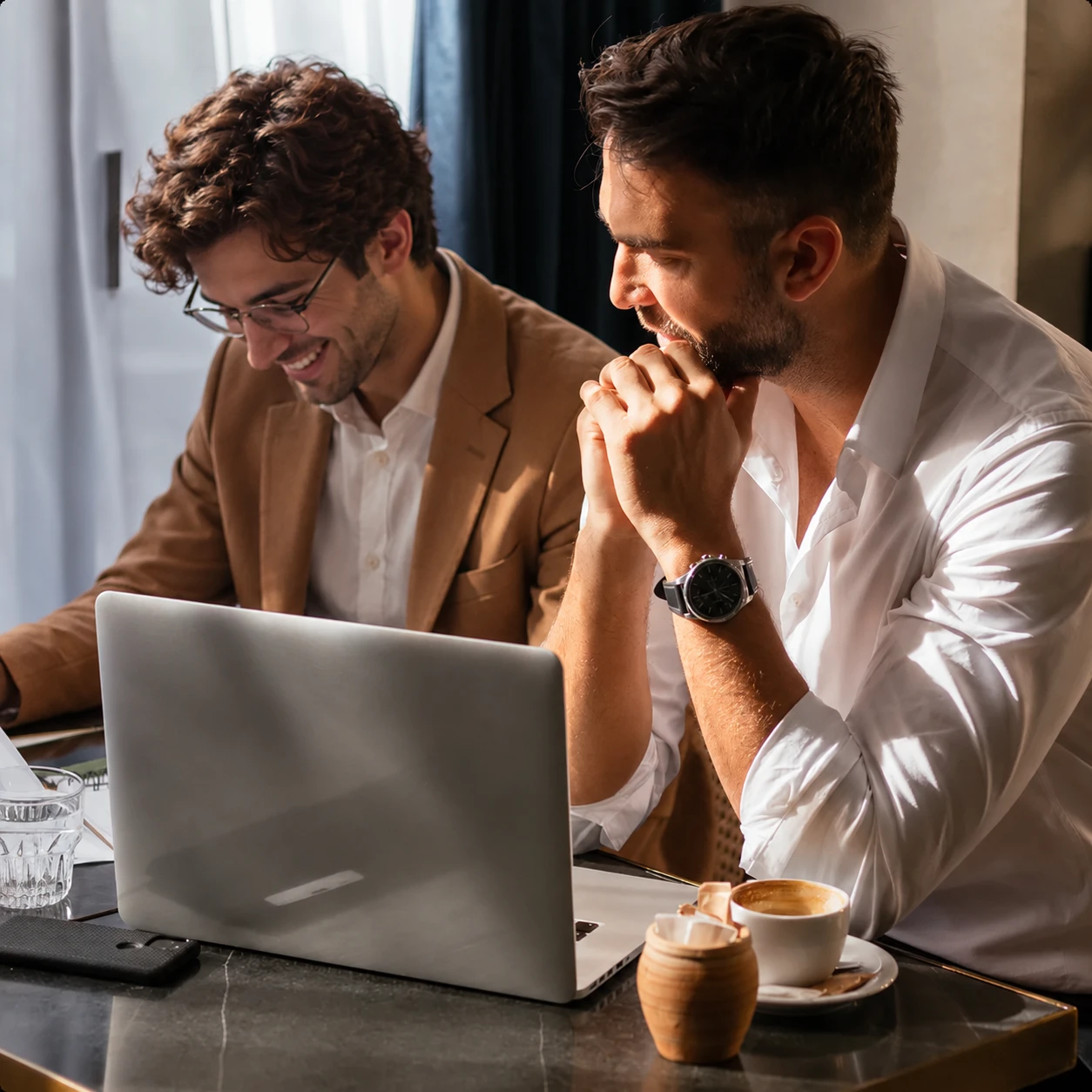 Two Apex Global Solutions colleagues sharing a laugh over a laptop